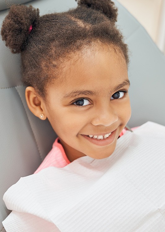 Smiling young girl in dental treatment chair