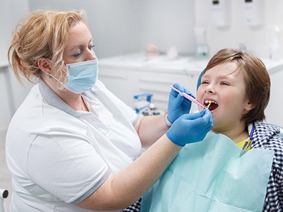 A dentist applying fluoride to a child’s teeth