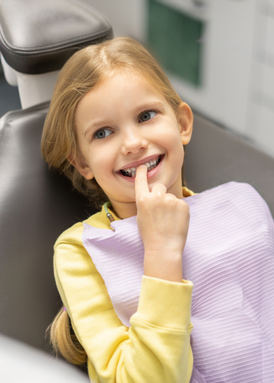 A girl pointing to her tooth at the dentist