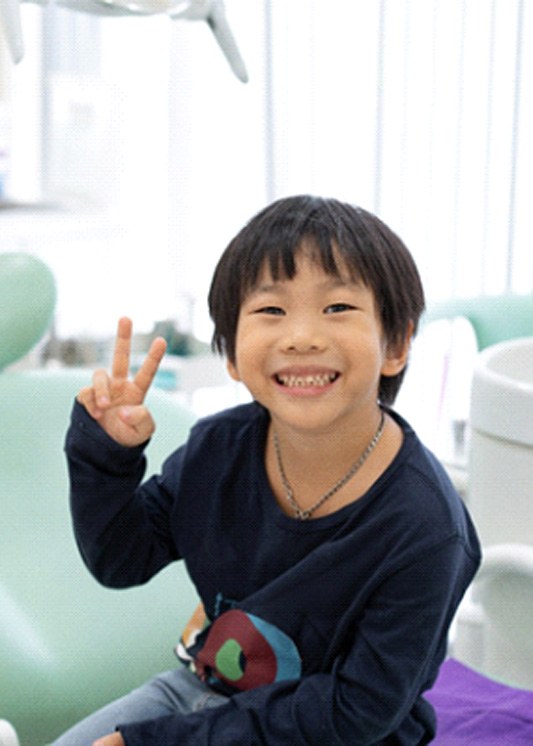 A boy giving a peace sign at the dentist