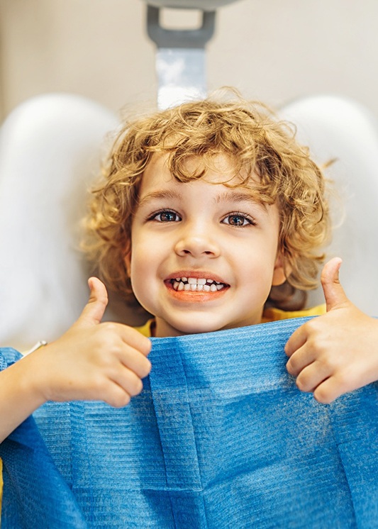 Pediatric dental patient giving two thumbs up