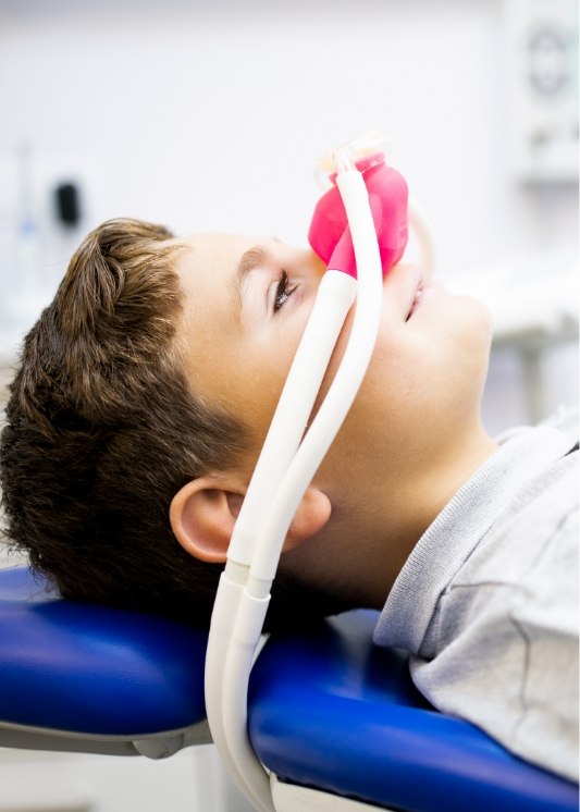 Boy in dental chair with nitrous oxide sedation dentistry mask on his face