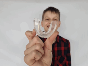 a child with an athletic mouthguard smiling